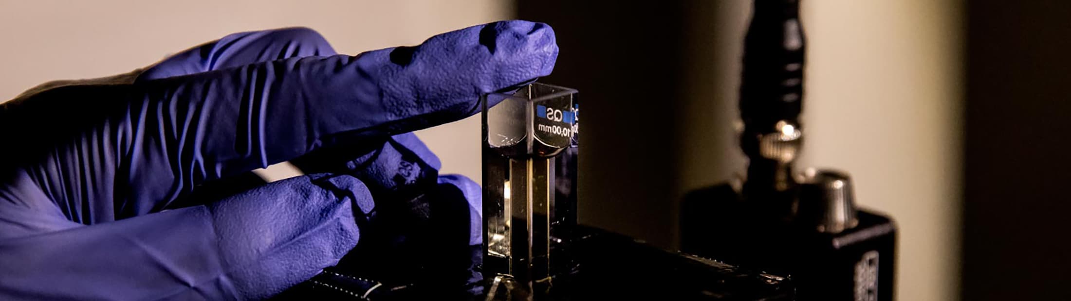 a close up image of a phd student applying a gel made up of chiromagnetic nanoparticles that are a conduit for modulating light to a laser apparatus