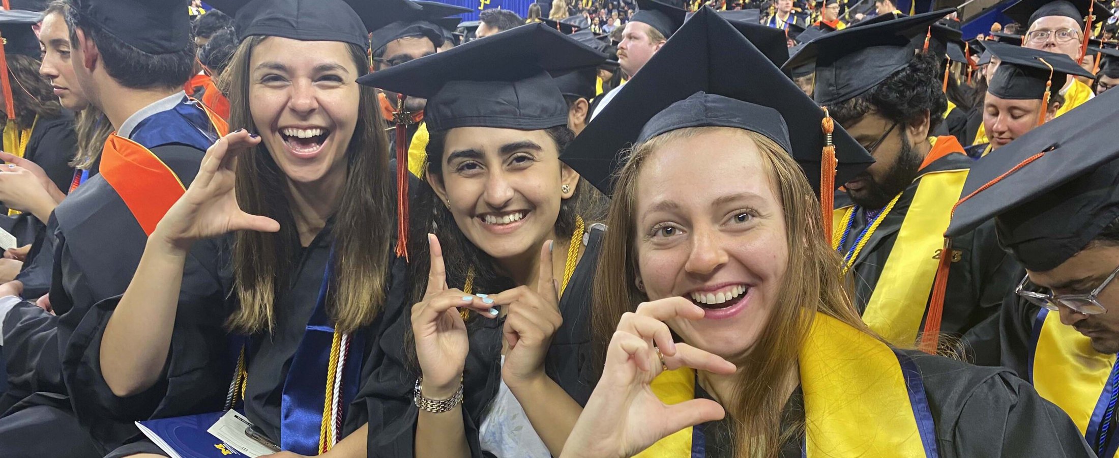 Students at commencement spell "ChE" with hands