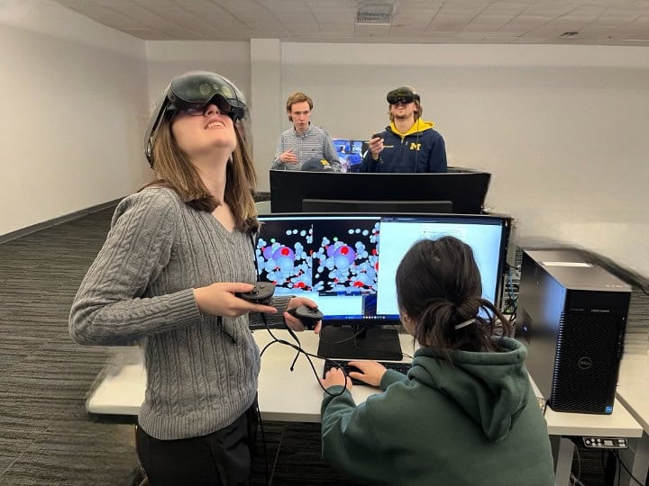 A group of students experiment with VR headsets in front of computers at the University of Michigan.